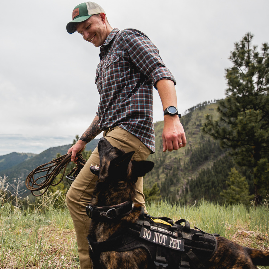 Handler with Dutch Shepherd in mountain meadow